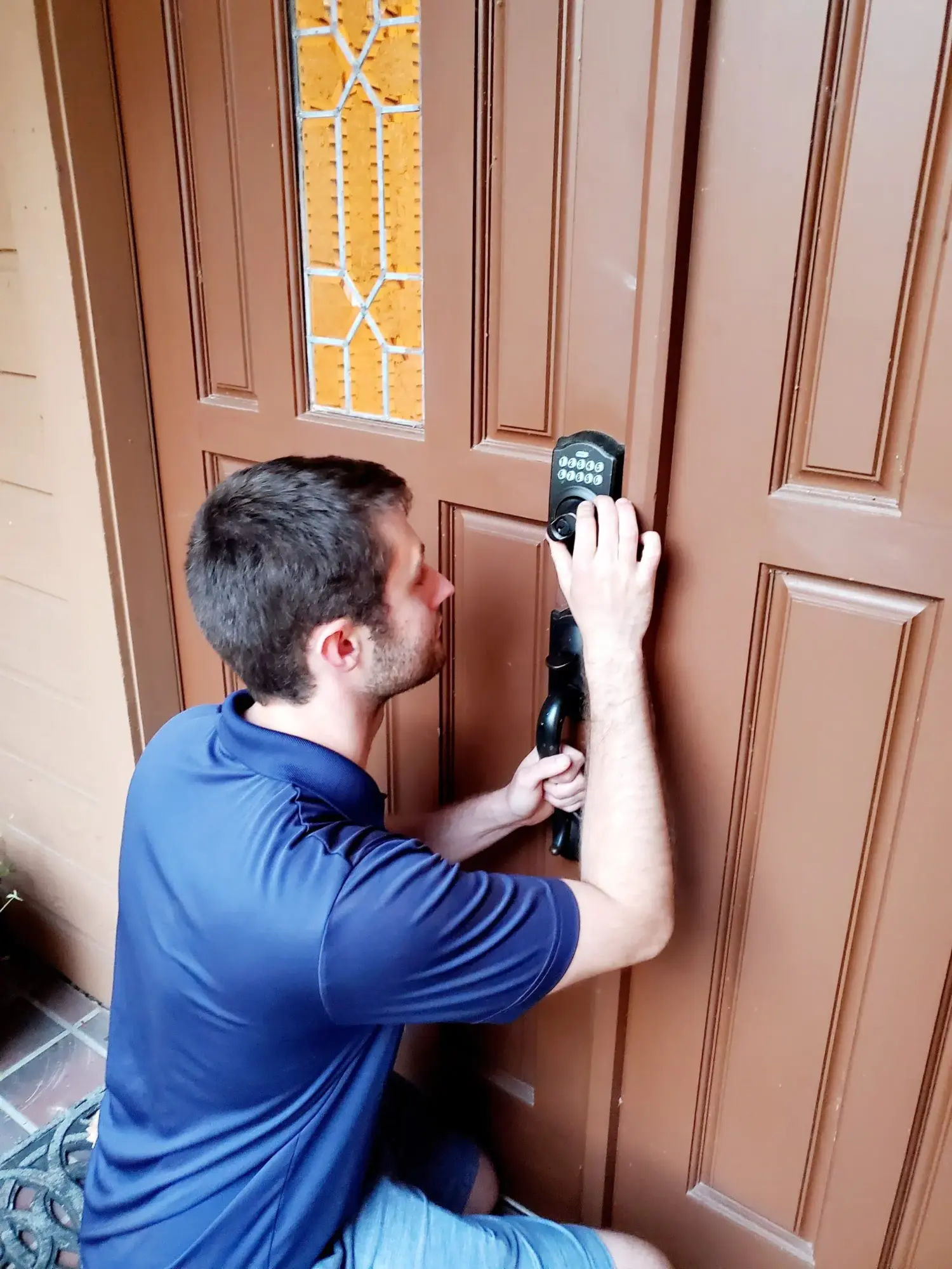Locksmith installing a smart keypad lock on a residential front door.